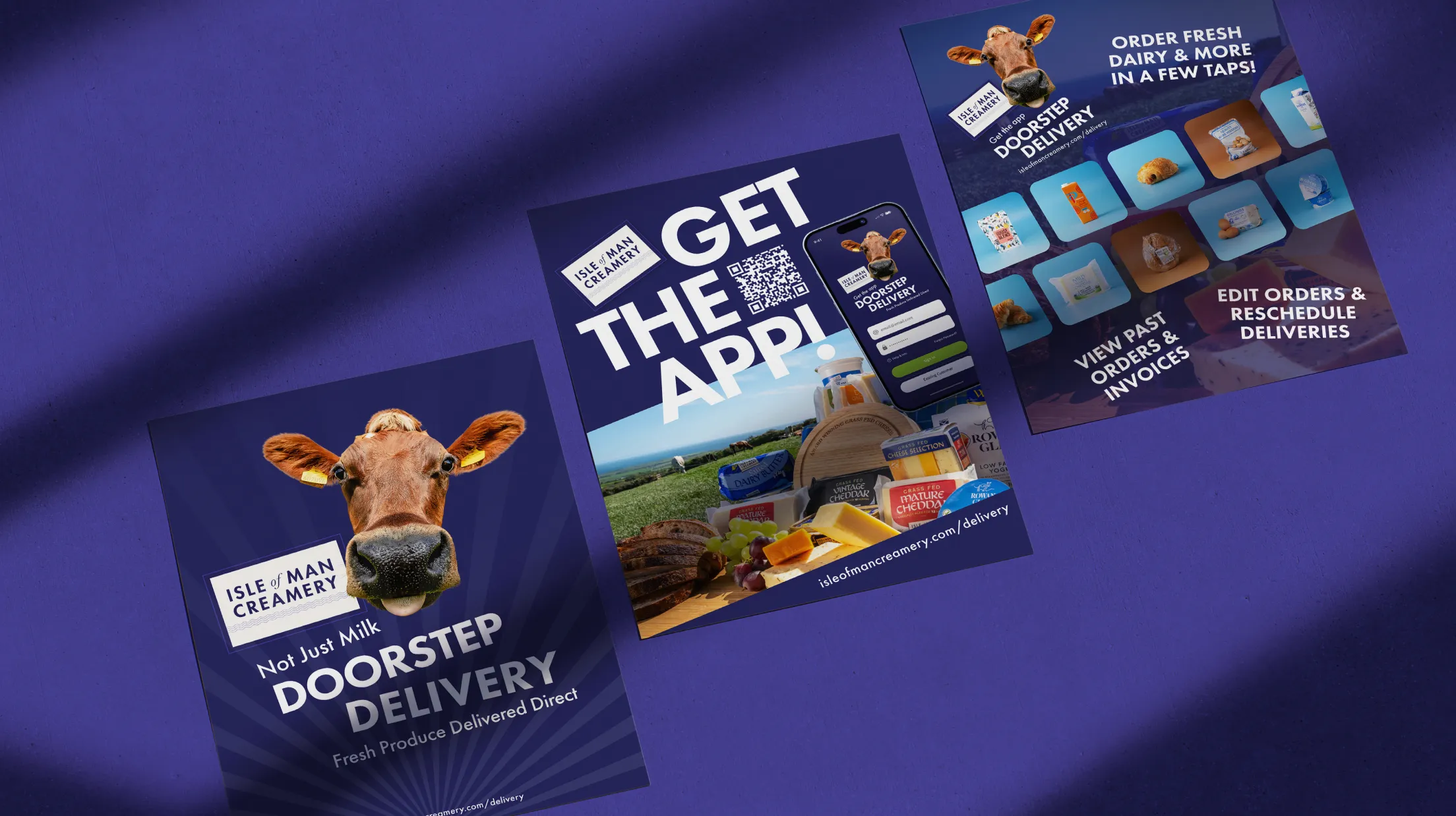 A flat lay of Isle of Man Creamery Doorstep Delivery promotional materials on a purple background, including a leaflet featuring a cow and "Not Just Milk" messaging, a "Get the App" poster with QR code, and a phone screen showing the app interface with order management features.